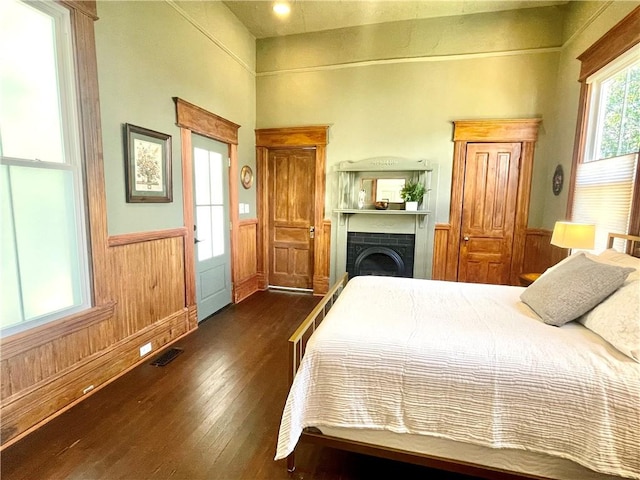 1915 Union St, Brunswick, GA 31520 - bedroom with wainscoting, dark wood-style floors, a fireplace, and wooden walls