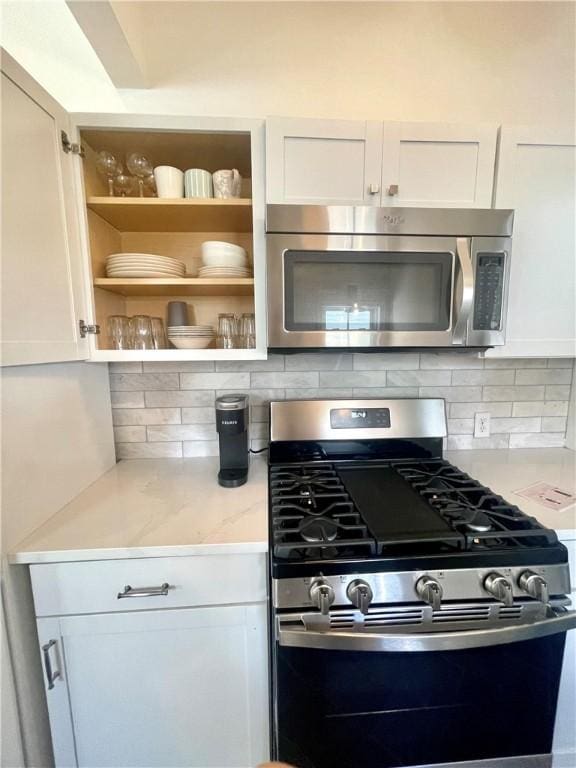 1915 Union St, Brunswick, GA 31520 - kitchen with appliances with stainless steel finishes, white cabinets, decorative backsplash, and light stone countertops