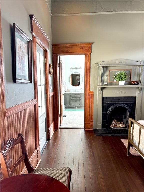 1915 Union St, Brunswick, GA 31520 - living room featuring dark wood finished floors, ornamental molding, a tiled fireplace, and wainscoting