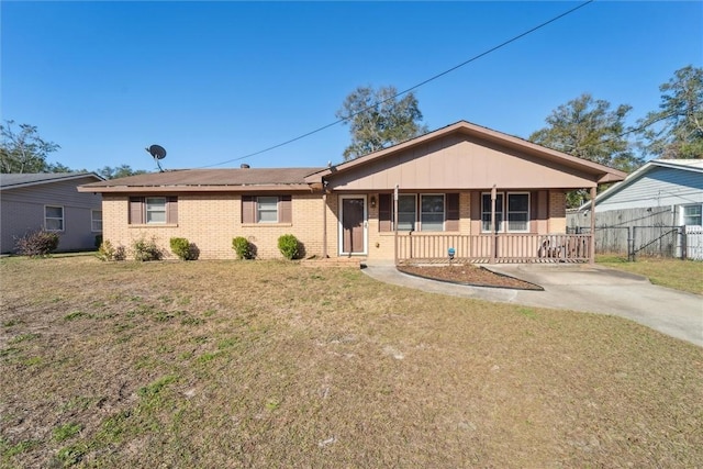 ranch-style house with covered porch, brick siding, fence, and a front lawn