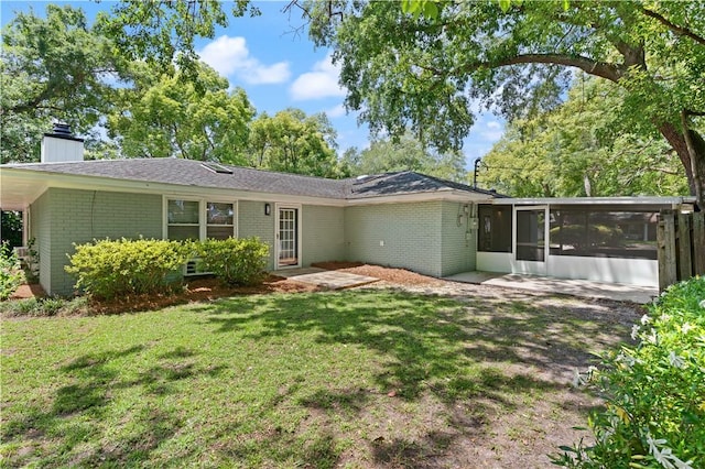 3120 Willow Ave, Brunswick, GA 31520 - rear view of house with brick siding, a sunroom, a chimney, and a lawn