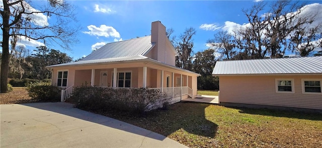 146 Don El St, Brunswick, GA 31523 - view of property exterior with covered porch, a metal roof, and a chimney