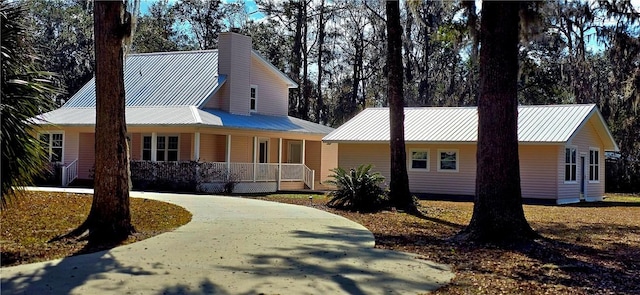 146 Don El St, Brunswick, GA 31523 - view of front of property featuring covered porch, a metal roof, curved driveway, and a chimney