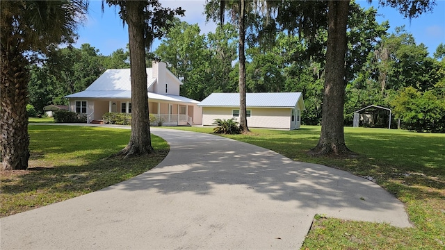 146 Don El St, Brunswick, GA 31523 - view of front of home featuring a front lawn, a porch, driveway, a chimney, and a metal roof