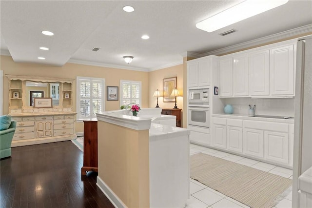 kitchen with white appliances, white cabinets, ornamental molding, a center island, and light countertops