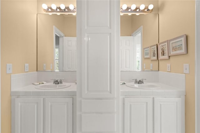 bathroom with two vanities, a sink, and a healthy amount of sunlight