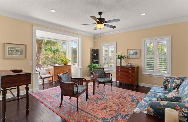 sitting room with dark wood-style floors, a textured ceiling, baseboards, and crown molding