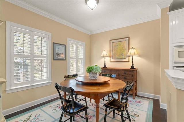 dining space featuring ornamental molding, baseboards, and wood finished floors