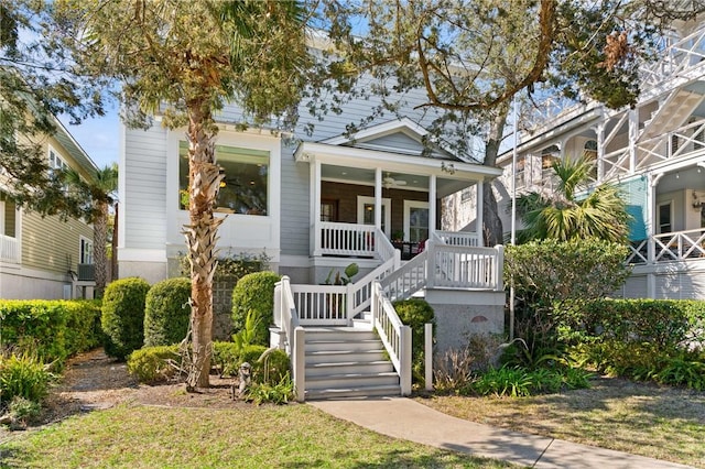 view of front of home featuring covered porch, ceiling fan, and stairway