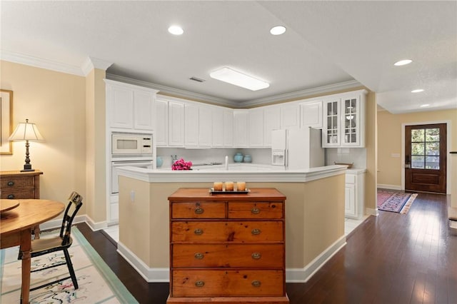 kitchen with crown molding, white appliances, hardwood / wood-style floors, and white cabinets