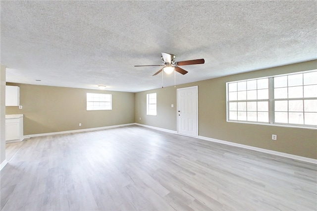 spare room with ceiling fan, light wood-style flooring, baseboards, and a textured ceiling