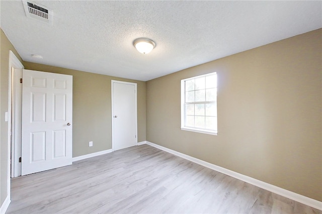 unfurnished bedroom with visible vents, light wood-style flooring, baseboards, and a textured ceiling