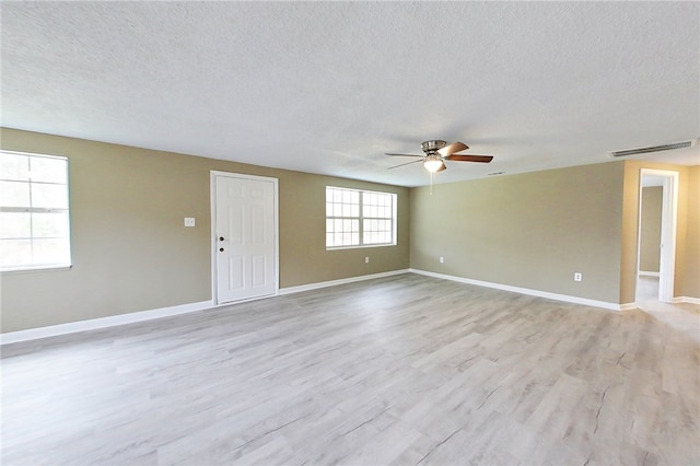 unfurnished room featuring light wood-style floors, baseboards, visible vents, and a textured ceiling