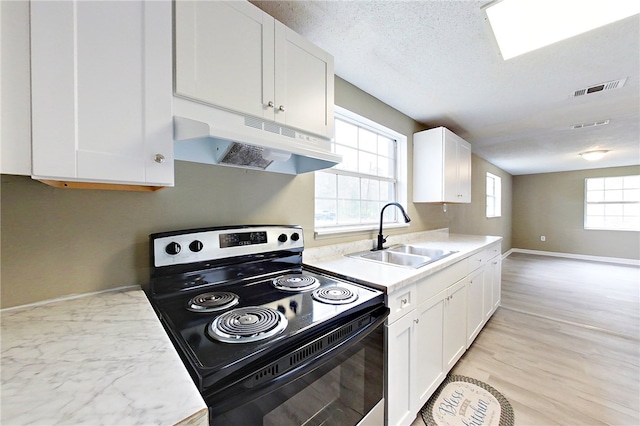 kitchen featuring under cabinet range hood, range with electric cooktop, a sink, white cabinetry, and light countertops