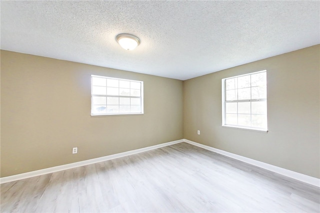 unfurnished room with baseboards, light wood-style flooring, and a healthy amount of sunlight