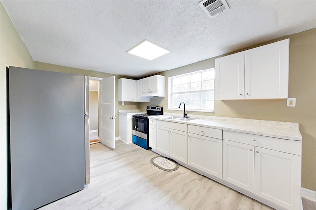 kitchen featuring a sink, white cabinetry, stainless steel appliances, and light countertops