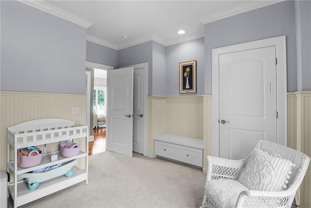 living area featuring a wainscoted wall, light carpet, and crown molding