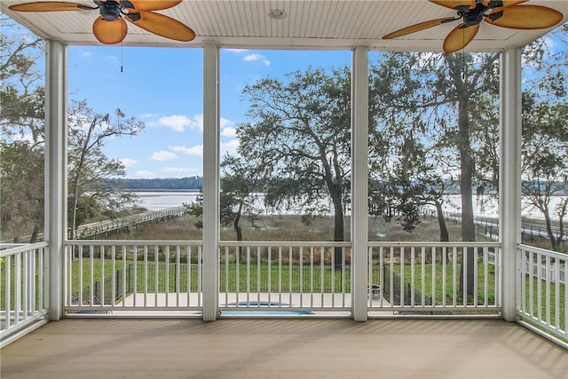 unfurnished sunroom with a ceiling fan and a water view