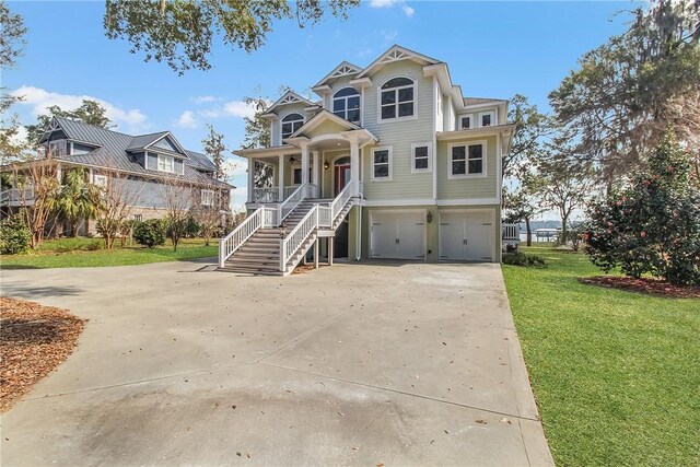 coastal inspired home with driveway, a front lawn, stairway, covered porch, and an attached garage