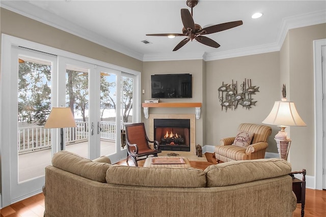 living area with baseboards, wood finished floors, a fireplace, and crown molding