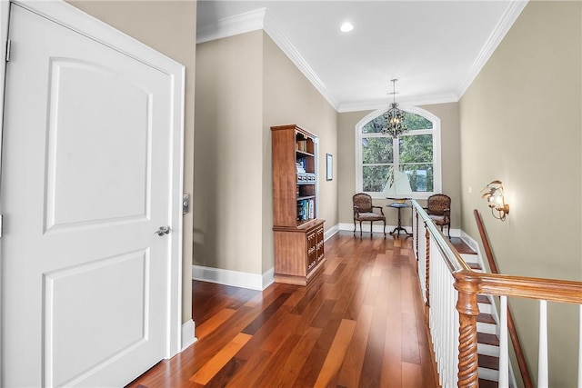 hallway featuring baseboards, an upstairs landing, dark wood-style floors, and ornamental molding