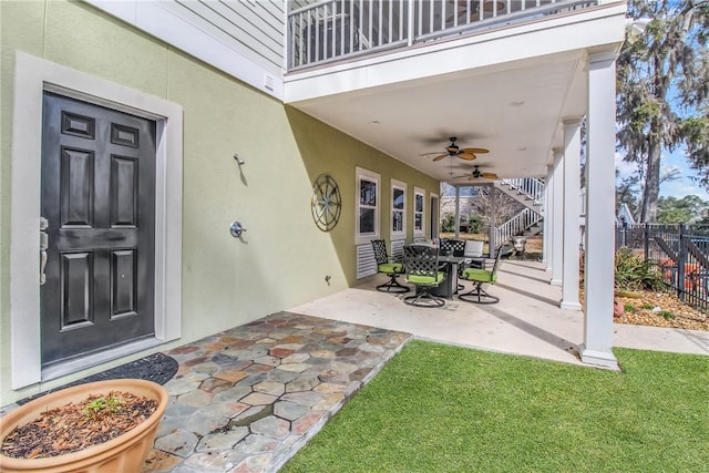 view of patio with stairway, a balcony, ceiling fan, and fence