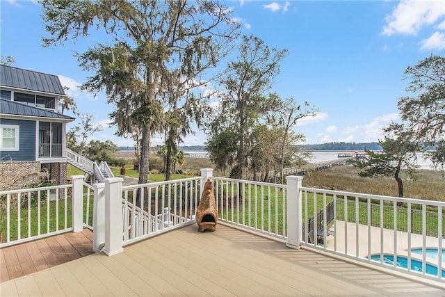 deck with an outdoor pool, stairway, and a water view