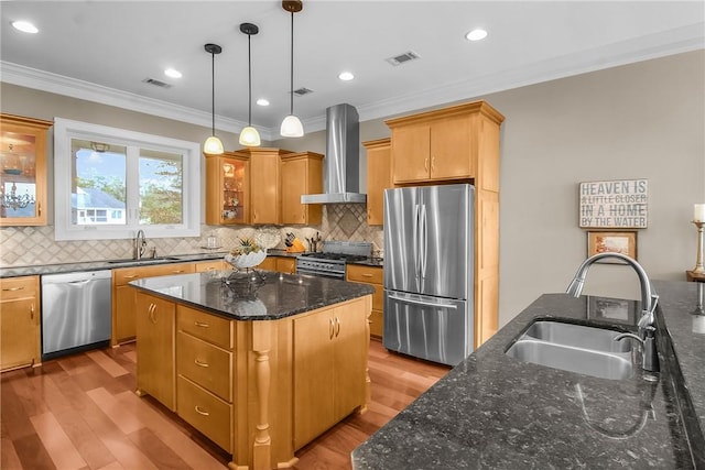 kitchen with a sink, visible vents, appliances with stainless steel finishes, and wall chimney range hood