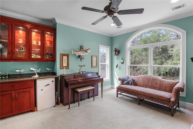 living area featuring visible vents, light colored carpet, baseboards, and ornamental molding