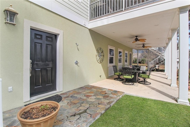 property entrance featuring a patio area, stucco siding, outdoor dining area, and a ceiling fan