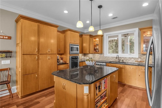 kitchen featuring light wood finished floors, visible vents, crown molding, appliances with stainless steel finishes, and a sink