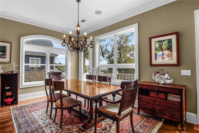 dining area featuring a notable chandelier, wood finished floors, baseboards, and ornamental molding