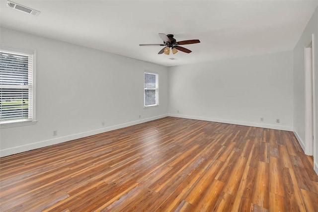 spare room featuring dark hardwood / wood-style floors, ceiling fan, and a healthy amount of sunlight