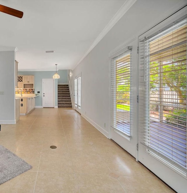 interior space with ceiling fan, light tile patterned flooring, and ornamental molding