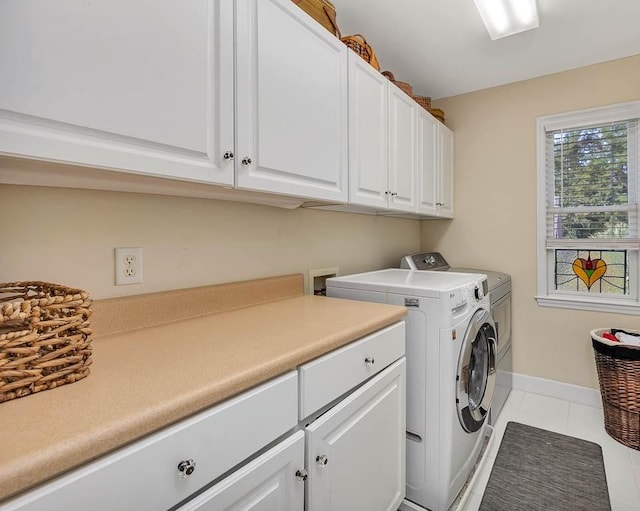 washroom with washing machine and dryer, light tile patterned floors, and cabinets