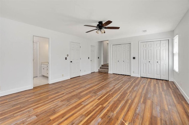 unfurnished bedroom featuring multiple closets, hardwood / wood-style floors, and ensuite bath