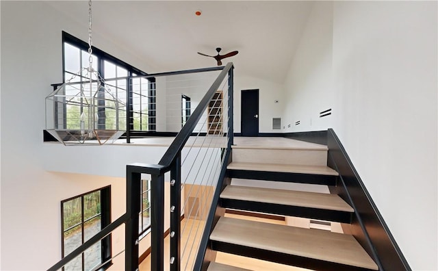 stairway with a high ceiling and an inviting chandelier