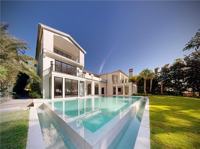 rear view of house with a lawn and a balcony