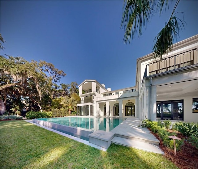 rear view of house featuring a patio area, a balcony, and a yard