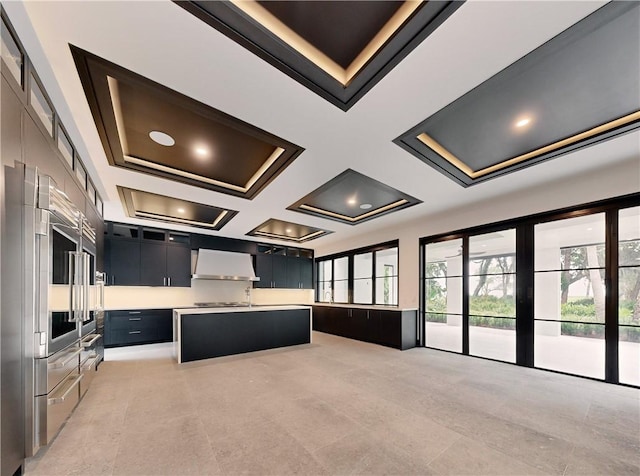 kitchen with coffered ceiling, a center island, beamed ceiling, and wall chimney range hood