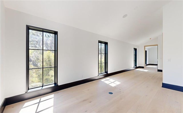 spare room featuring light hardwood / wood-style floors and vaulted ceiling