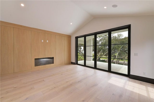 unfurnished living room featuring lofted ceiling and light hardwood / wood-style flooring