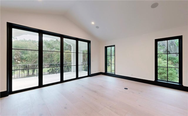 unfurnished room featuring a healthy amount of sunlight, lofted ceiling, and light wood-type flooring