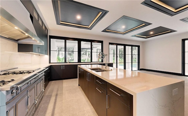 kitchen with french doors, stainless steel cooktop, a spacious island, sink, and wall chimney range hood