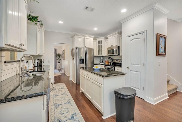 kitchen with visible vents, glass insert cabinets, dark wood-style floors, stainless steel appliances, and a sink