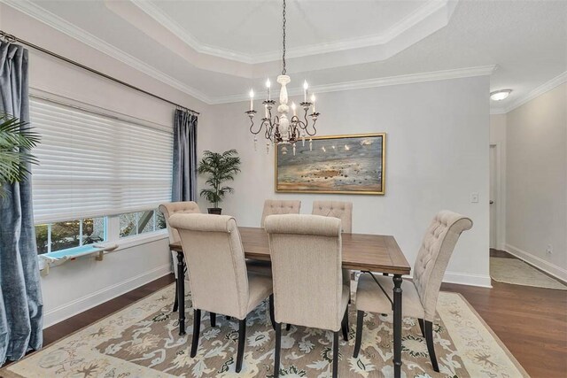 dining area featuring crown molding, baseboards, a chandelier, a tray ceiling, and wood finished floors