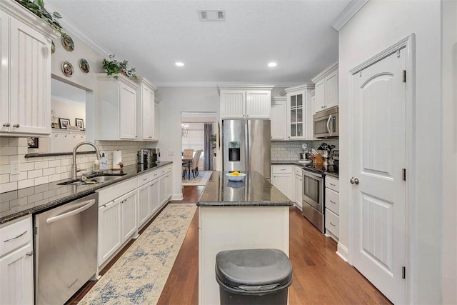 kitchen with a sink, stainless steel appliances, visible vents, and crown molding