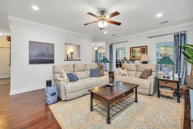 living room with a ceiling fan, wood finished floors, visible vents, baseboards, and crown molding