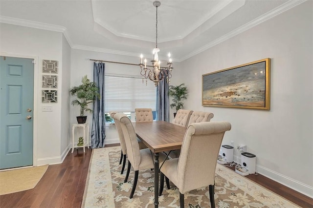 dining space with a chandelier, baseboards, a tray ceiling, and wood finished floors