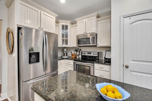 kitchen with decorative backsplash, dark stone countertops, appliances with stainless steel finishes, and glass insert cabinets